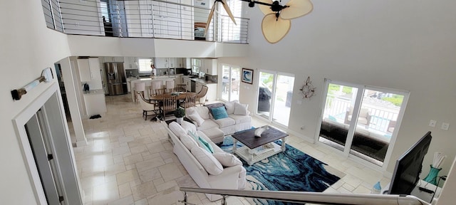 living area with plenty of natural light, baseboards, a high ceiling, and stone tile floors