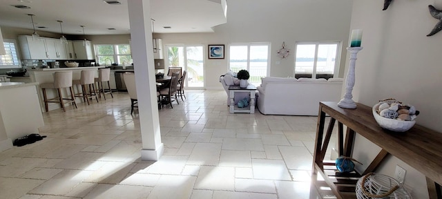 living area featuring baseboards, visible vents, and stone tile flooring