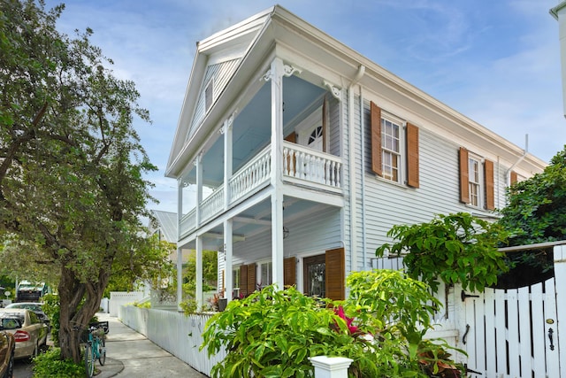 view of property exterior featuring a porch, fence, and a balcony