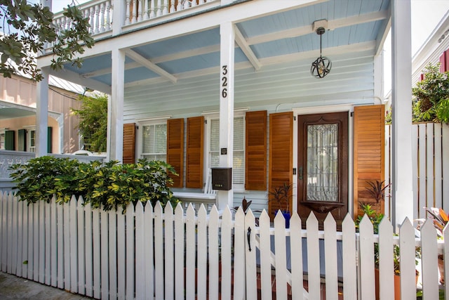 property entrance featuring covered porch and fence