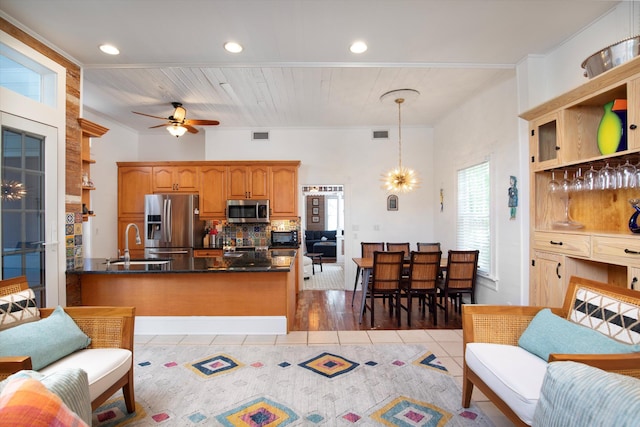 kitchen with light tile patterned floors, appliances with stainless steel finishes, backsplash, a peninsula, and a sink