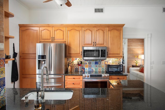 kitchen with visible vents, appliances with stainless steel finishes, a ceiling fan, a sink, and dark stone counters