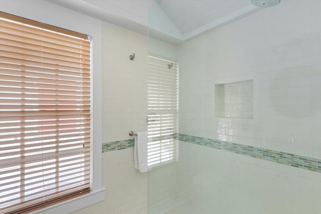 full bathroom with vaulted ceiling and a tile shower