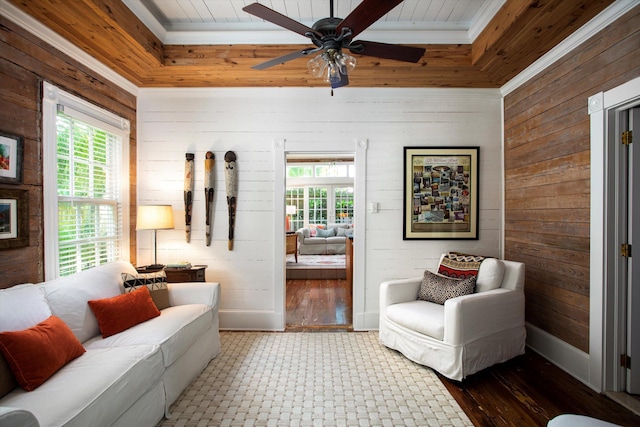 living room featuring plenty of natural light, wooden walls, and baseboards