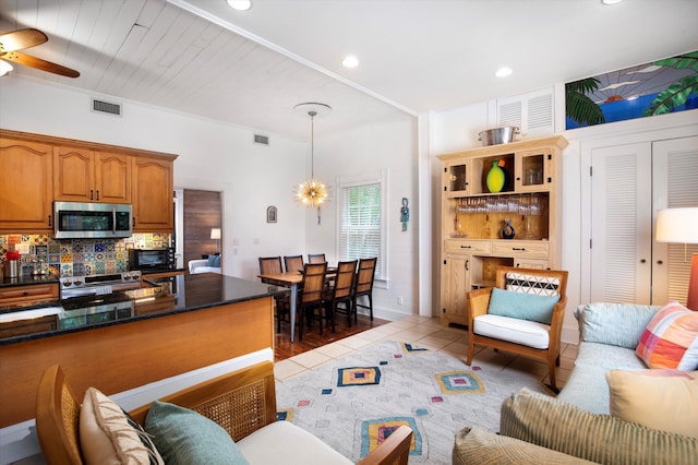 living area with ceiling fan with notable chandelier, dark tile patterned flooring, visible vents, and recessed lighting