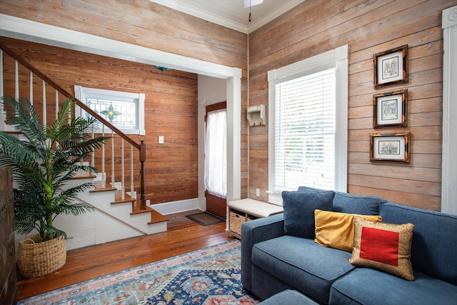 living area with a healthy amount of sunlight, wood walls, stairs, and wood finished floors