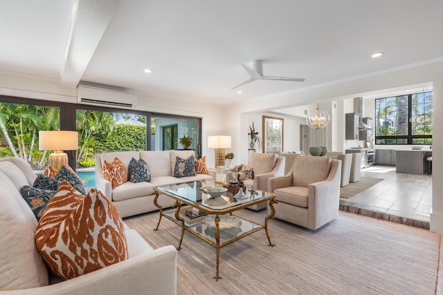 living room with beamed ceiling, a wall mounted air conditioner, a healthy amount of sunlight, and ceiling fan with notable chandelier