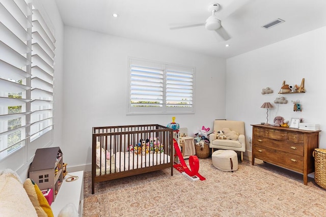 bedroom with a nursery area and ceiling fan