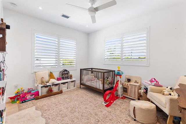 bedroom with a nursery area and ceiling fan