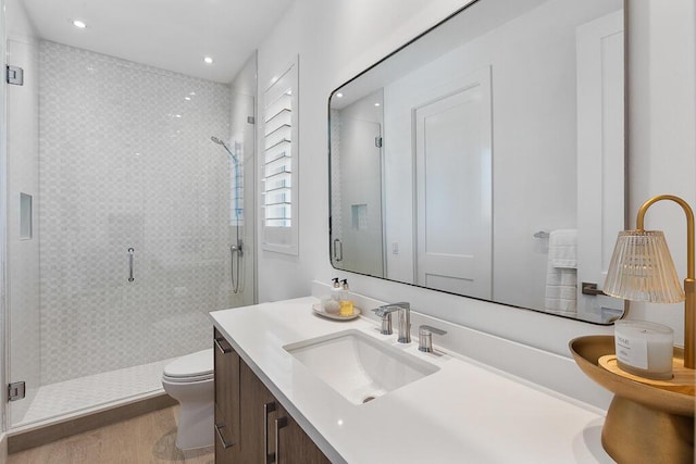 bathroom featuring hardwood / wood-style flooring, vanity, toilet, and a shower with shower door