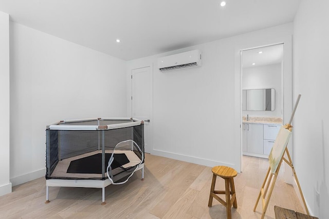 misc room with a wall mounted air conditioner and light hardwood / wood-style floors