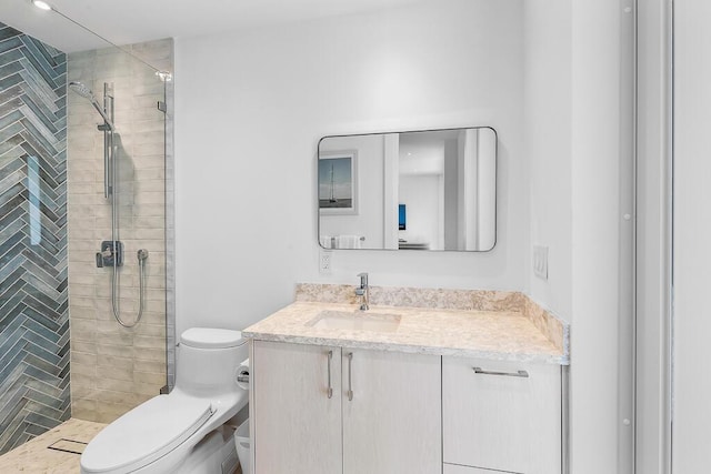 bathroom featuring tiled shower, vanity, and toilet