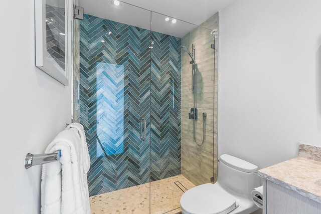 bathroom featuring vanity, toilet, and a tile shower