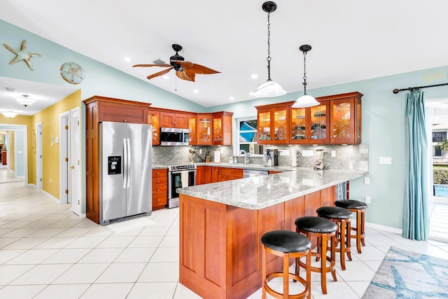 kitchen with appliances with stainless steel finishes, decorative light fixtures, kitchen peninsula, and light tile patterned floors