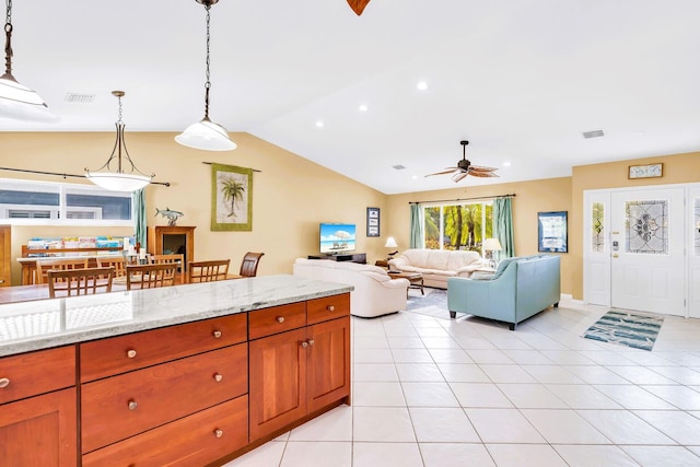 kitchen with light stone counters, decorative light fixtures, vaulted ceiling, and light tile patterned flooring