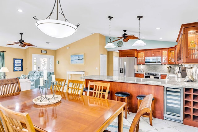 dining space with wine cooler, vaulted ceiling, ceiling fan, and light tile patterned flooring