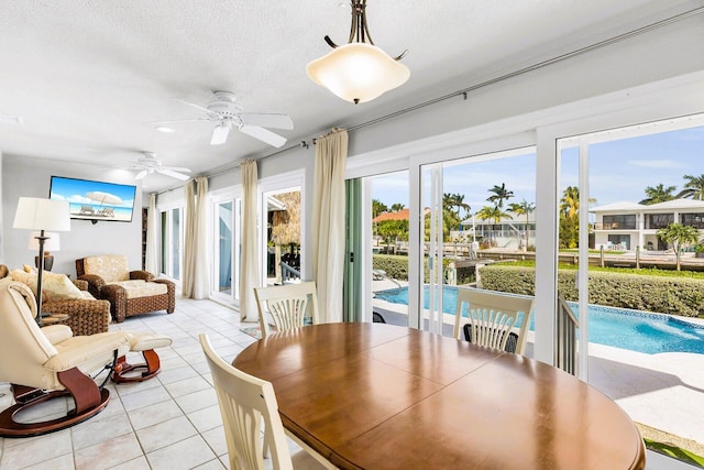 tiled dining space with ceiling fan and a textured ceiling