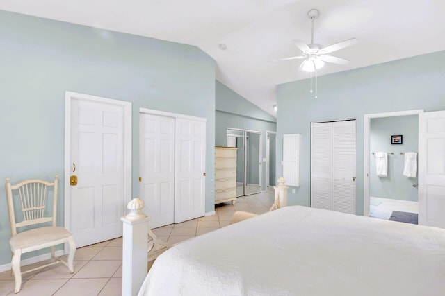 bedroom featuring multiple closets, connected bathroom, vaulted ceiling, and light tile patterned floors