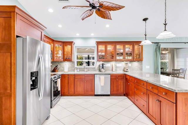 kitchen featuring light stone countertops, appliances with stainless steel finishes, decorative light fixtures, and kitchen peninsula