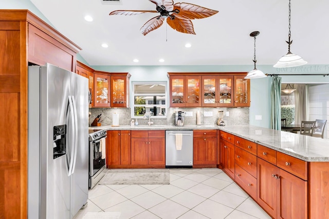 kitchen featuring sink, hanging light fixtures, stainless steel appliances, light stone counters, and kitchen peninsula