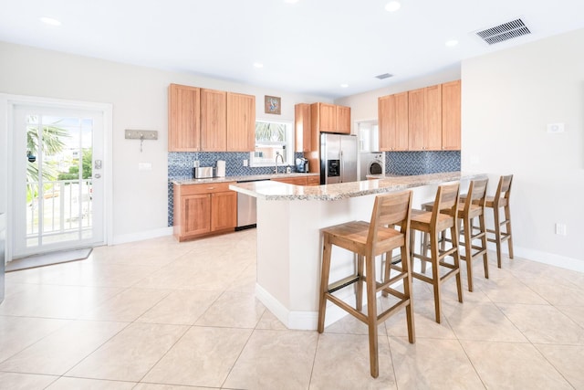 kitchen featuring light tile patterned floors, a kitchen breakfast bar, stainless steel appliances, washer / clothes dryer, and kitchen peninsula