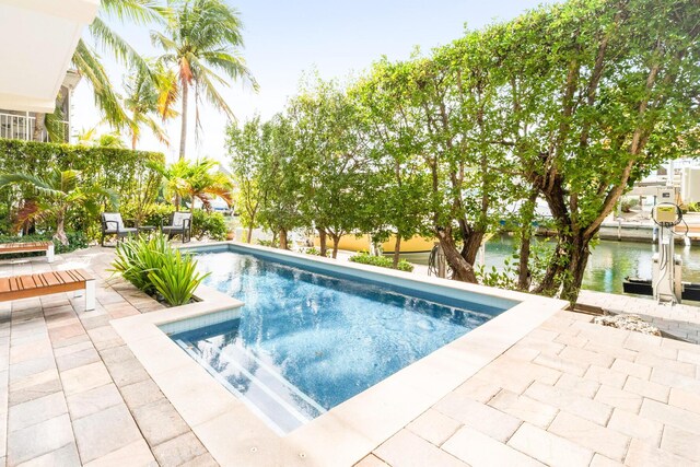 view of swimming pool featuring a water view and a patio area