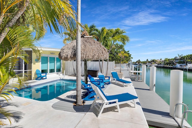view of swimming pool featuring fence, a patio, a boat dock, a fenced in pool, and a water view