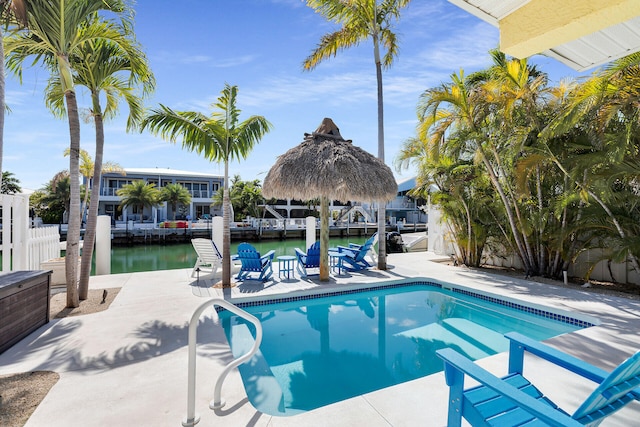 outdoor pool featuring a water view, fence, and a dock