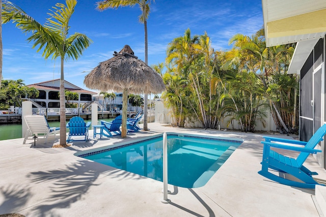 pool with a patio, a dock, and a water view