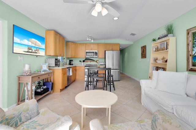 living area with visible vents, a ceiling fan, baseboards, light tile patterned floors, and vaulted ceiling