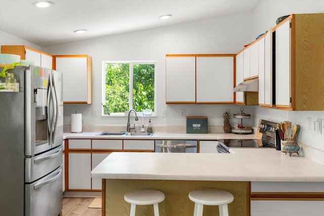 kitchen with white cabinetry, sink, stainless steel appliances, and kitchen peninsula