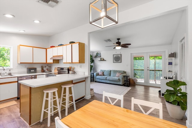 kitchen featuring sink, stainless steel electric range, white cabinetry, hanging light fixtures, and kitchen peninsula