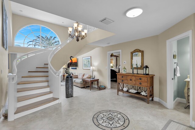 foyer entrance featuring visible vents, stairway, an inviting chandelier, light tile patterned flooring, and baseboards