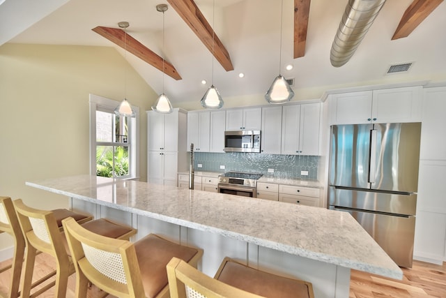 kitchen with visible vents, decorative backsplash, a breakfast bar area, white cabinets, and stainless steel appliances