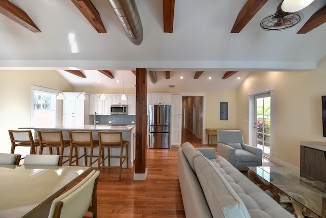 living area with recessed lighting, vaulted ceiling with beams, and light wood finished floors