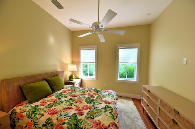 bedroom with baseboards, ceiling fan, visible vents, and wood finished floors