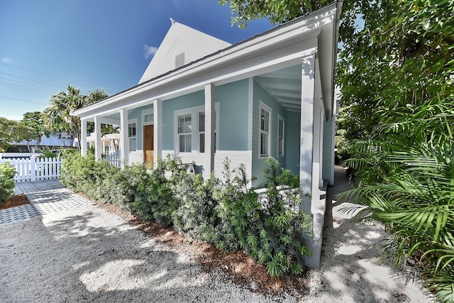 view of home's exterior with a porch and fence
