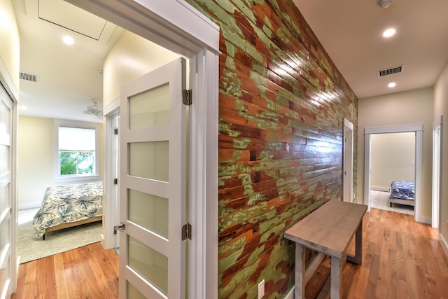 corridor with visible vents, recessed lighting, light wood-style flooring, and brick wall