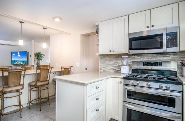 kitchen with white cabinetry, decorative light fixtures, stainless steel appliances, and kitchen peninsula