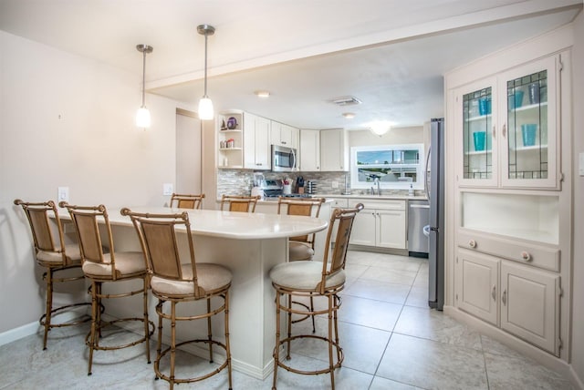 kitchen with sink, decorative light fixtures, stainless steel appliances, decorative backsplash, and white cabinets