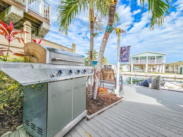 wooden terrace featuring grilling area, a dock, and a water view