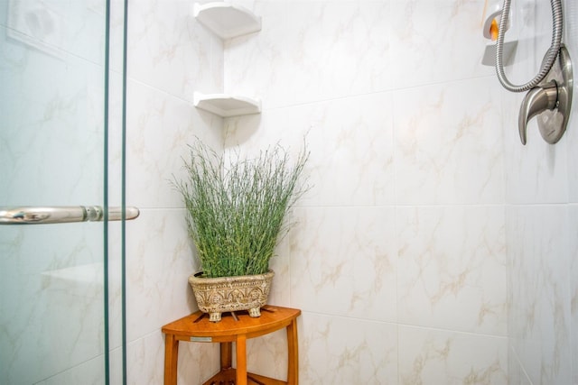 bathroom with a shower with shower door and tile walls