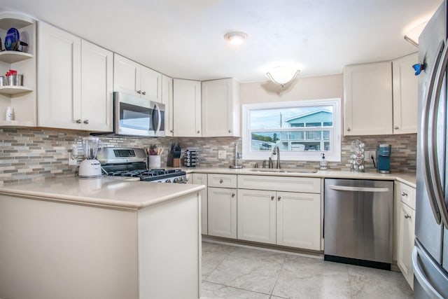 kitchen with sink, white cabinetry, kitchen peninsula, stainless steel appliances, and backsplash