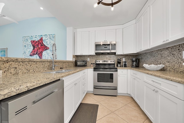 kitchen featuring stainless steel appliances, sink, light tile patterned floors, and white cabinets