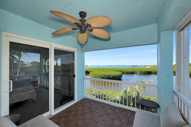 unfurnished sunroom with a water view and ceiling fan