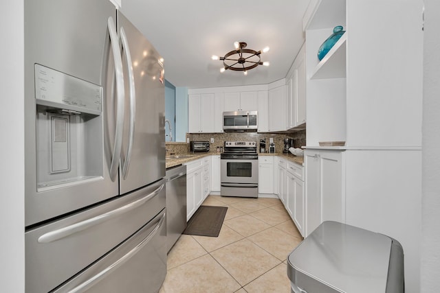 kitchen featuring white cabinets, decorative backsplash, light tile patterned floors, light stone counters, and stainless steel appliances