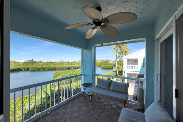 sunroom featuring a water view and ceiling fan