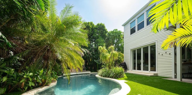 outdoor pool featuring french doors and a yard