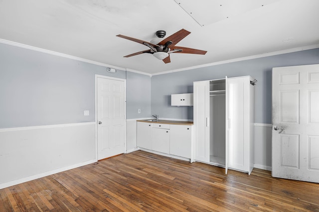 unfurnished bedroom featuring crown molding, baseboards, wood-type flooring, and ceiling fan