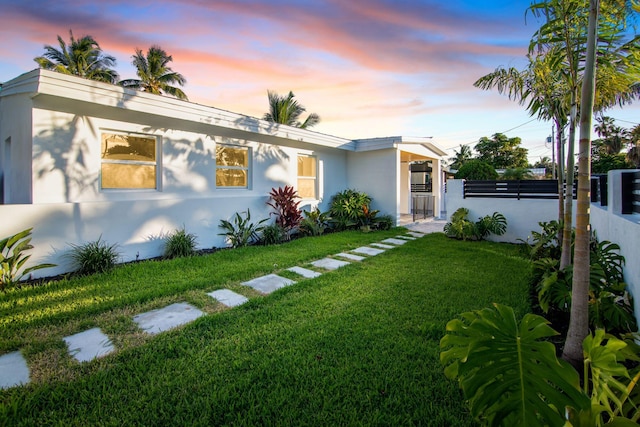 view of front of home with a lawn, fence, a gate, and stucco siding